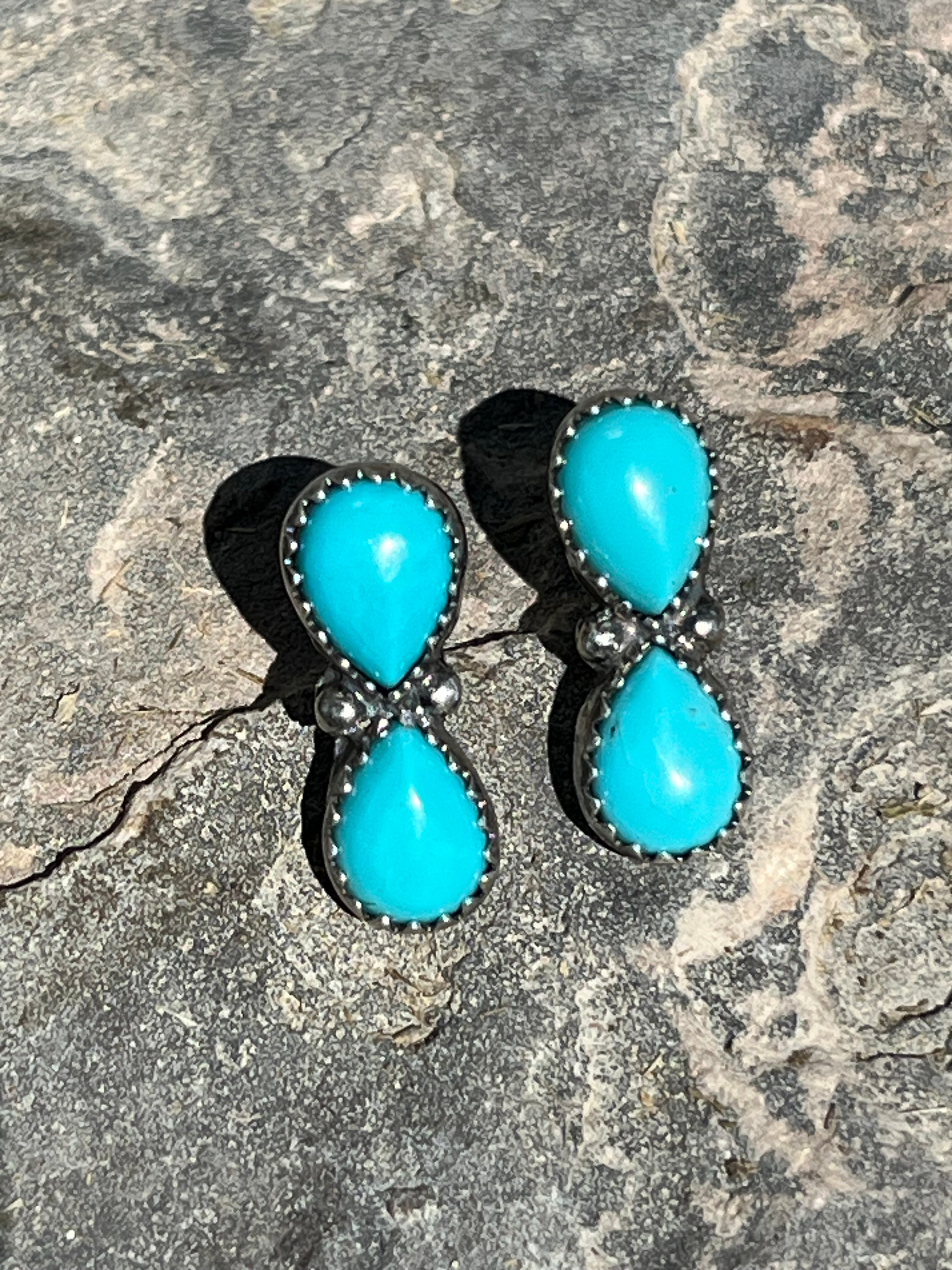 Pair of turquoise stone earrings on a textured stone surface